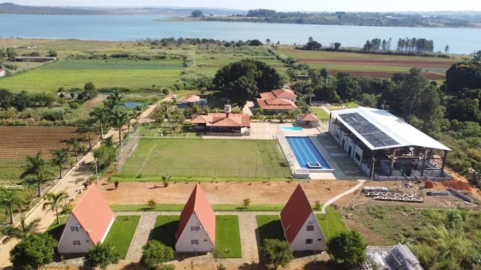 Vista aérea da Villa do Galo: campo de futebol, piscina, chalés e o lago ao fundo